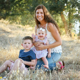 Mom sitting down with son and baby daughter on yellow dry grass in Folsom