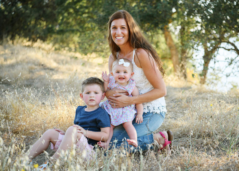 Mom sitting down with son and baby daughter on yellow dry grass in Folsom