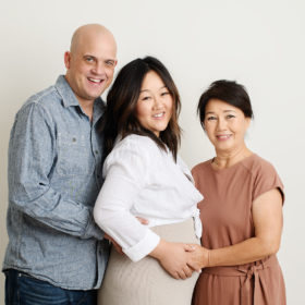 Husband, pregnant wife and mom hugging in Sacramento studio