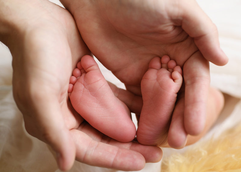 Tiny newborn baby feet being held by mom's hands