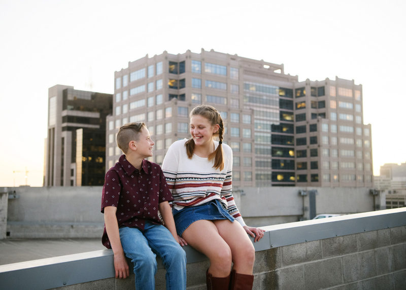 Brother and sister sitting on Sacramento rooftop overlooking cityscape