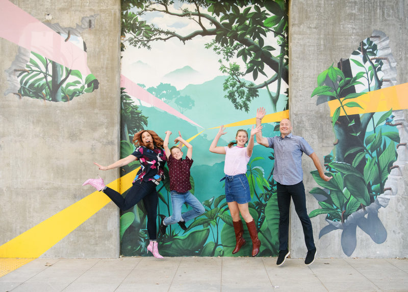 Family jumping and smiling in front of Kinetik Ideas R Street mural 