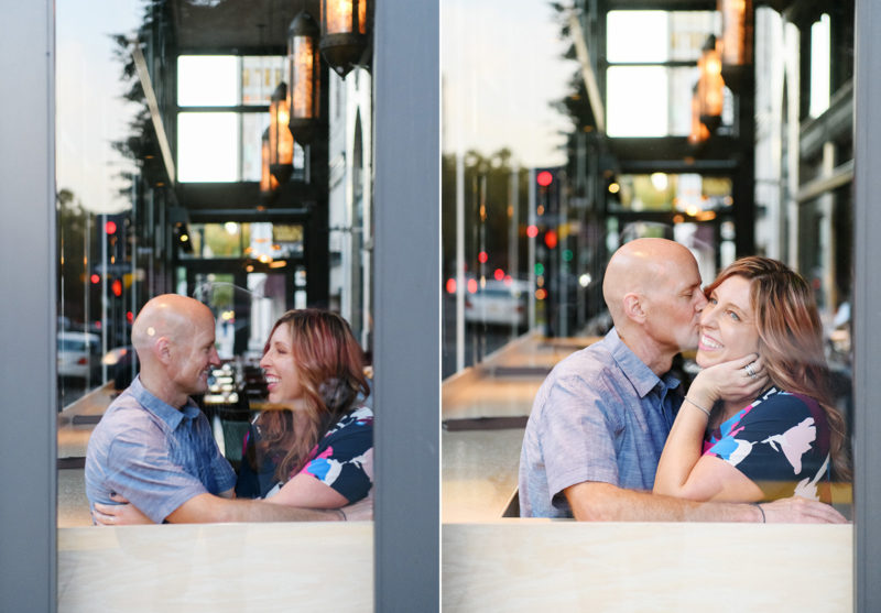 Mom and dad kissing and looking at each other lovingly in cafe through window in Sacramento