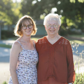 Mom and grandma smile and hug in front of Sacramento lawn