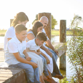 Family sitting on the dock and dipping their feet into the lake in Sacramento