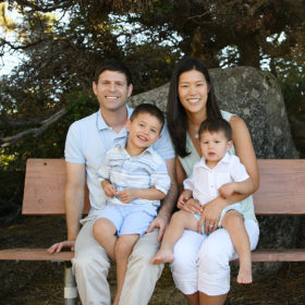 Mom and dad holding toddler boys in laps on bench at Lake Tahoe
