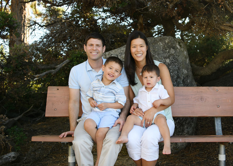 Mom and dad holding toddler boys in laps on bench at Lake Tahoe