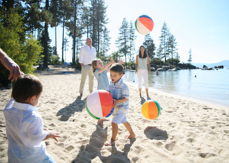 Families tossing around beach balls in the sand at Lake Tahoe