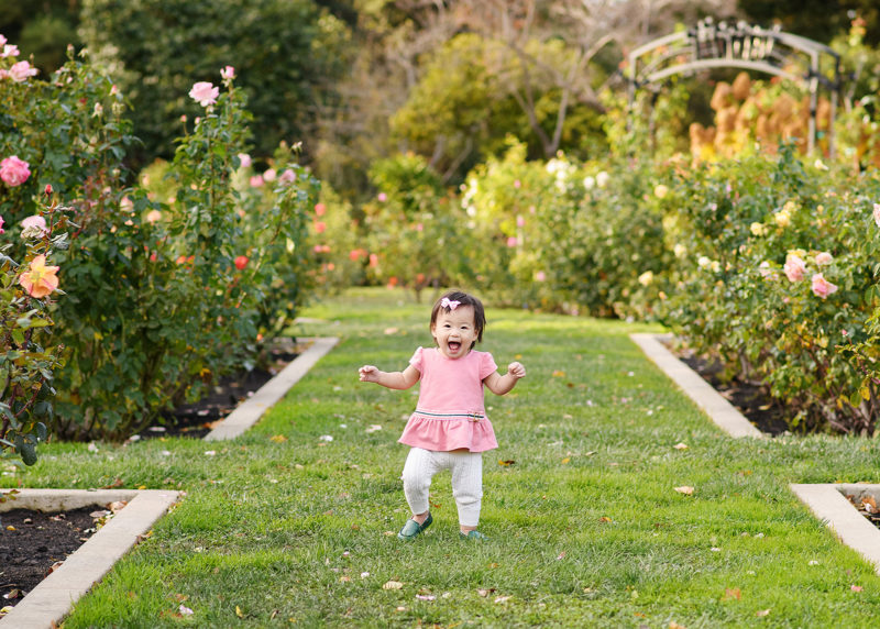 Toddler girl running through grass at the Rose Garden in McKinley Park Sacramento