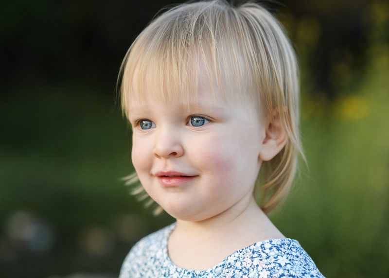 Blonde toddler girl with blue eyes close up outdoors in Fair Oaks