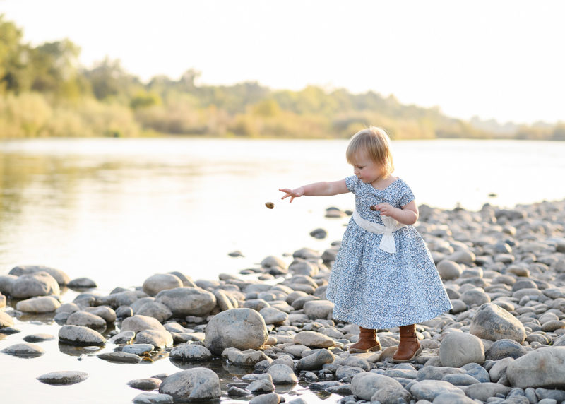 Toddler girl skipping rocks by lake in Fair Oaks