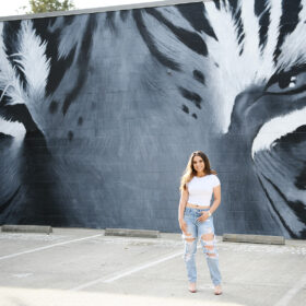 High school senior girl standing in front of tiger mural in downtown Sacramento