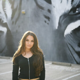 High school senior girl standing in the sun in front of tiger mural in downtown Sacramento