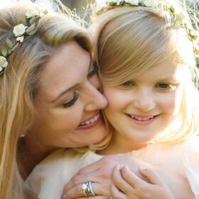 Mom and daughter hugging and smiling while wearing flower crowns