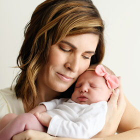 Mom cradling newborn baby girl by face in Sacramento studio