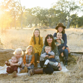 Grandma group picture with grandchildren sitting on dry grass and a log in Folsom