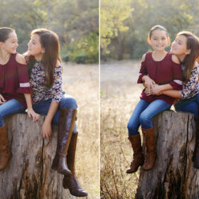 Sisters hugging and looking at each other while sitting on tree stump in Cameron Park
