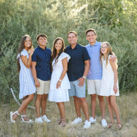 Family portrait wearing shades of blue with green trees as a background in Folsom Lake