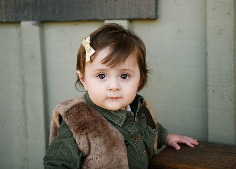 Toddler girl in fur vest looks directly in camera in Old Sacramento