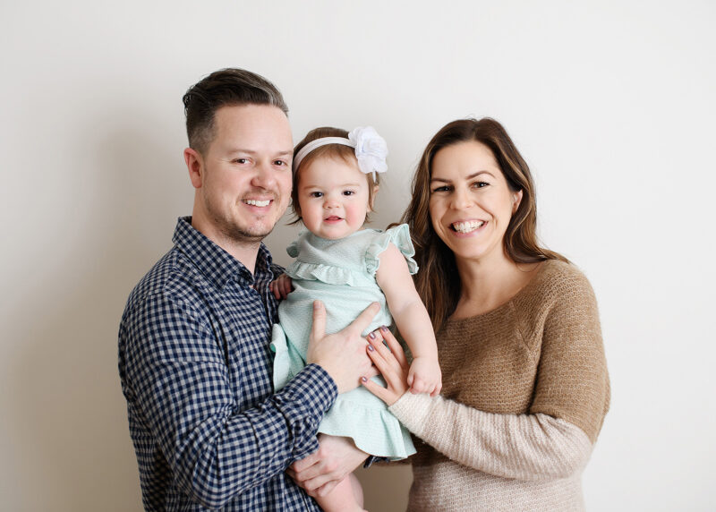 Parents holding one year old daughter and smiling in Sacramento studio