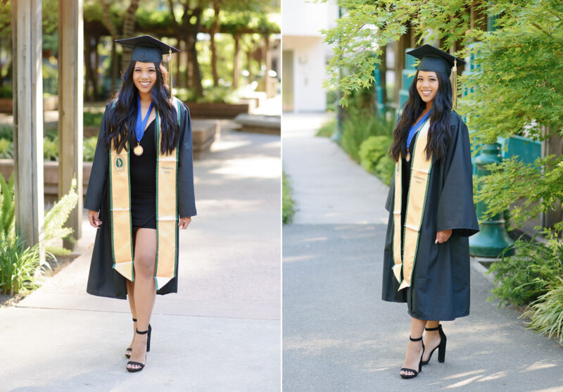 Sacramento State college graduate girl walking towards camera wearing cap and gown and smiling with trees in background