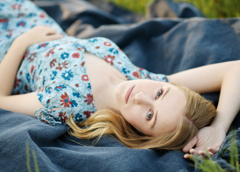 Teen girl lying down on blue blanket in Sacramento