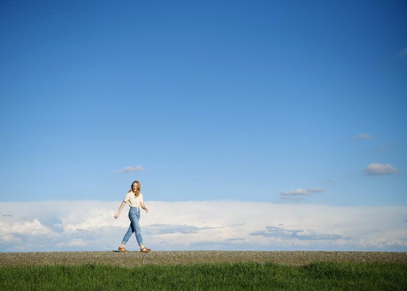 Teen girl walking against big blue sky horizon in Sacramento