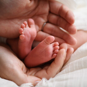 Close up of newborn baby feet being held by dad’s hands in Sacramento studio