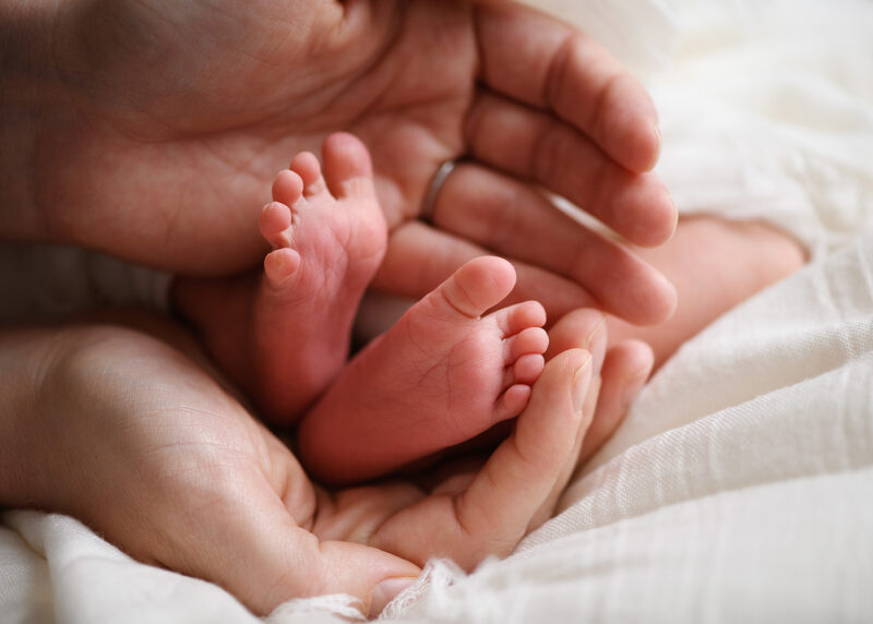 Close up of newborn baby feet being held by dad's hands in Sacramento studio