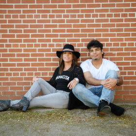 Teenage boy with his mom sitting on ground against brick background in Old Sacramento