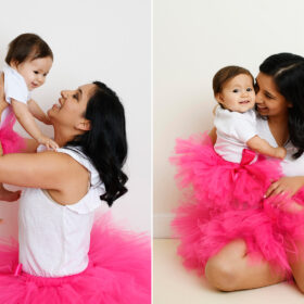 One year old daughter and mom wears pink tutus and smile for the camera in Sacramento studio