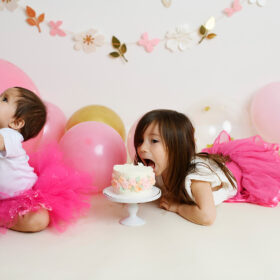Big sister tries to eat little sister’s birthday cake while dressed in pink tutus in Sacramento studio
