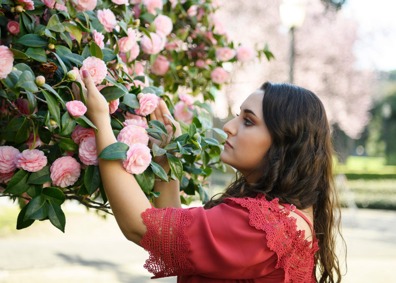 Teen girl admiring pink roses at Sacramento State Capitol