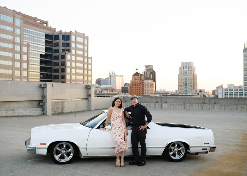 Teen girl posing with dad in white classic car on Sacramento rooftop