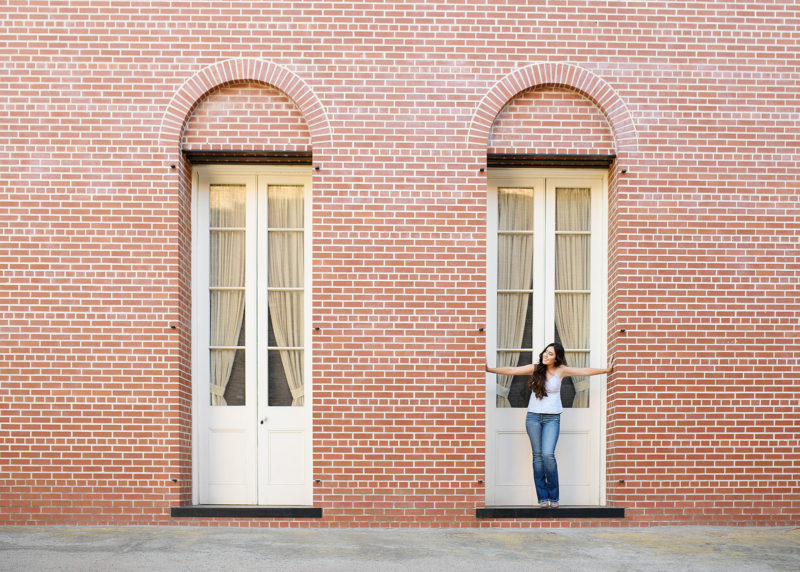 Teen girl standing in front of framed doorway on brick building in Old Sacramento