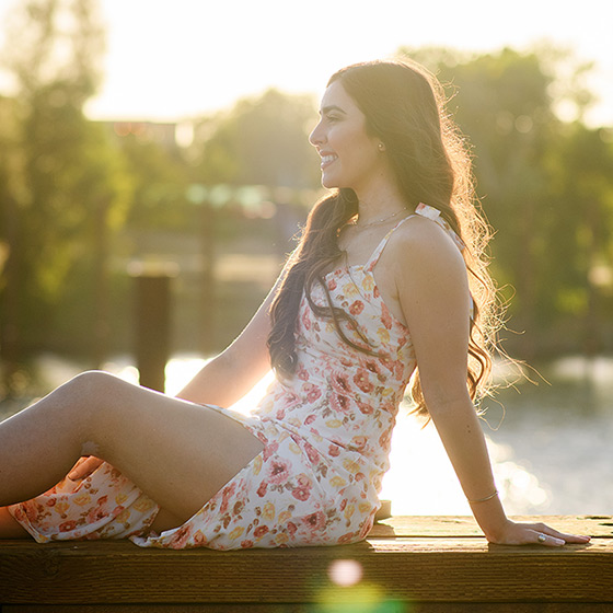 Senior girl posing in front of Sacramento waterfront during sunset wearing long dress golden hour