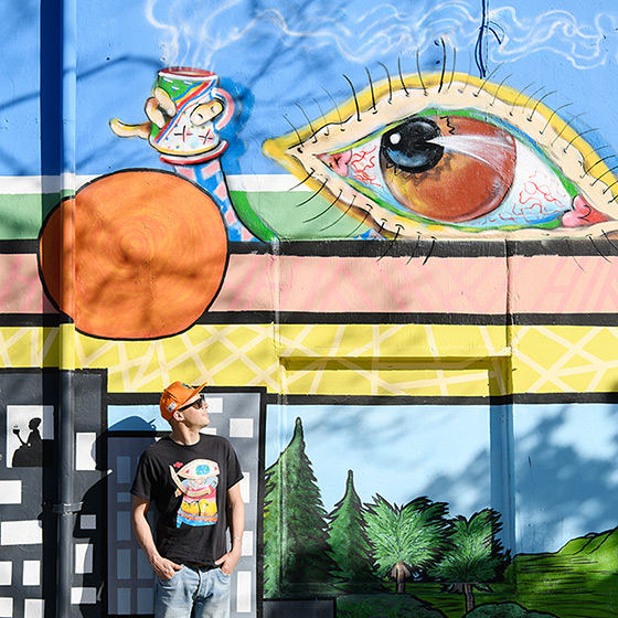 Artist standing in front of his artwork mural