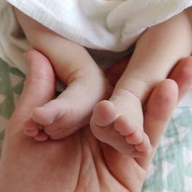 Closeup of newborn tiny feet being held by hands shot by camera phone