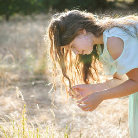 Girl looking at dry grass with long hair in sunshine in Davis