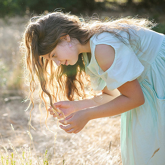 Girl looking at dry grass with long hair in sunshine in Fair Oaks
