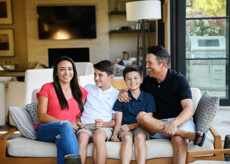 Dad and sons look at mom and smile on the couch in Sacramento home