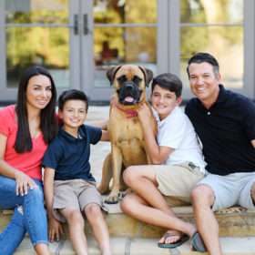 Family poses with their dog sitting on steps of backyard steps in Sacramento home