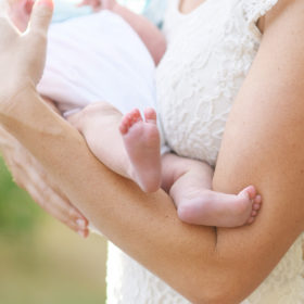 Close up of newborn baby girl feet as mom holds her outside in Rocklin park