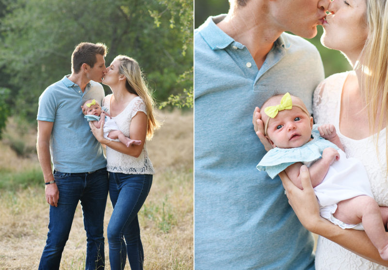 Mom and dad kiss while holding newborn baby girl in dry grass field in Rocklin