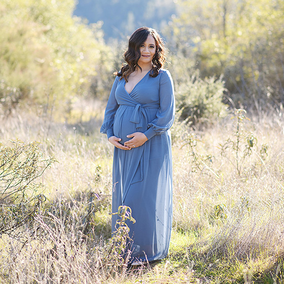 Pregnant woman wearing powder blue maxi dress standing in dry grass field Sacramento