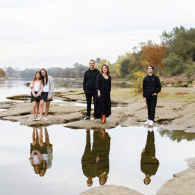 Family standing on rocks by the water with reflection on lake Sacramento