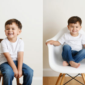 Toddler boy smiling and sitting on mid-century modern white chair and crossing legs in Sacramento studio