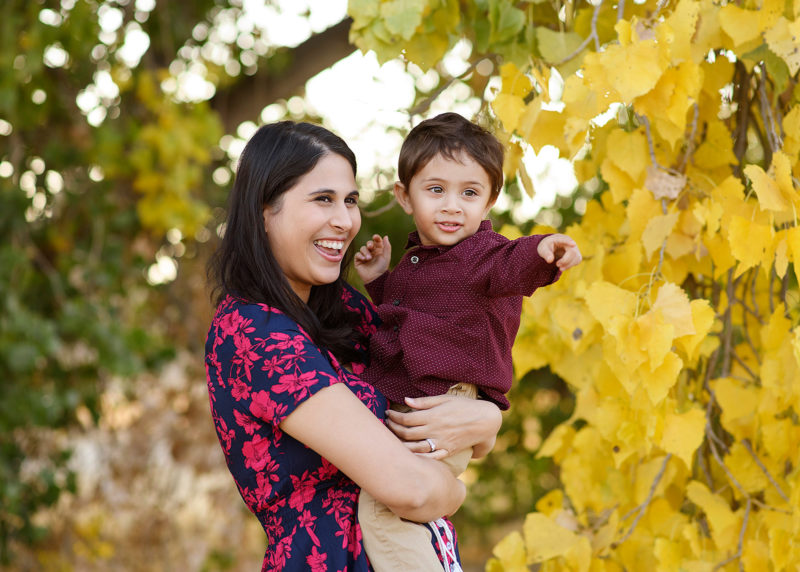 Mom holding son as he points with yellow leaves on trees framing the picture Folsom