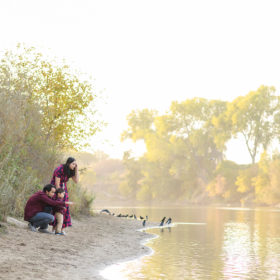 Family crouched down on the sand by the lake during sunset in Folsom