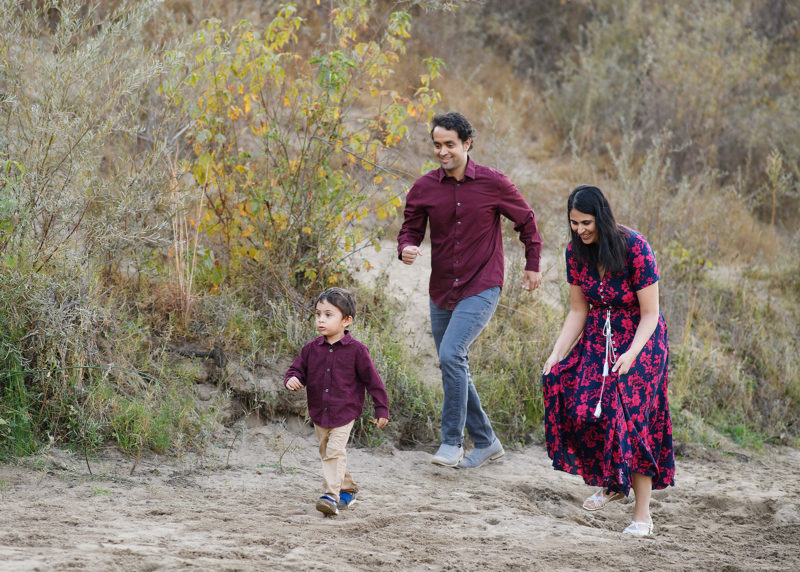 Little boy running in the sand as mom and dad run after in Folsom